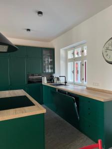 a kitchen with green cabinets and a clock on the wall at Rychtrova bouda Benecko in Benecko
