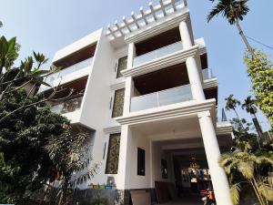 a white building with palm trees in front of it at Buddha Premium Stays in Guwahati