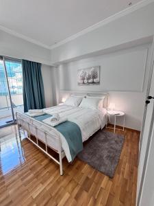 a white bedroom with a large bed and a window at Relax - Patras Apartment in Patra