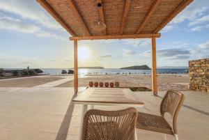 a patio with a table and chairs on the beach at Lipsi Grand Villas in Leipsoi