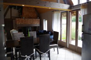 ein Esszimmer mit einem Tisch, Stühlen und einem Kamin in der Unterkunft Ndila Cottage avec piscine exclusive in Fatouville-Grestain