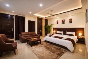 a bedroom with a bed and a couch and a chair at Hotel Prime Stay in Noida +32 photos