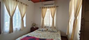 a bedroom with a bed and two windows at Gangadharam Tiny House 2BHK AC in Tellicherry