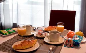 a table with a breakfast of croissants and orange juice at Le Petit Majestic in Lourdes