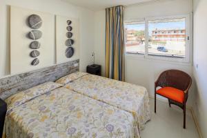 a bedroom with a bed and a chair and a window at Apartamentos Rodamar in L'Estartit +16 photos