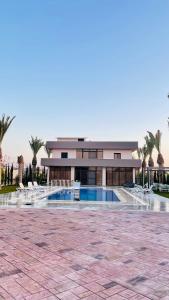 a building with a swimming pool and palm trees at Villa W2 in Amman