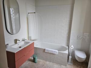 a bathroom with a tub and a sink and a toilet at Château de la Follie Le Berne in Pierrefonds