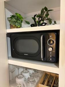 a black microwave in a cabinet with some plants at The Nest at Forest Lake - Stylish Guest Suite in Kangaroo Flat