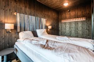 a bedroom with two beds in a wooden wall at Kikut Alpin Lodge 2102 in Hol