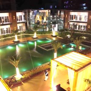 a building with a fountain with palm trees and lights at Riyank Farms in Patna +4 photos