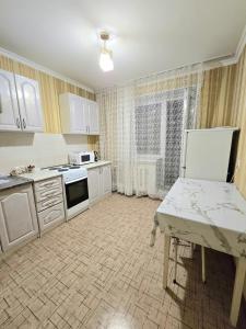 a kitchen with white cabinets and a table in it at Аэропорт Астана 5 минут 1 in Astana