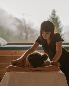 a woman sitting on a bed with a woman laying on a pillow at Chalet Noèr in Ledro