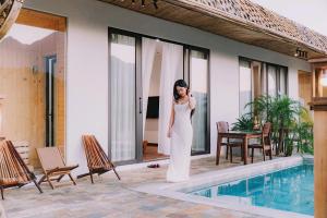 a woman in a white dress standing next to a swimming pool at Thung May Resort - Venuestay in Ba Vì