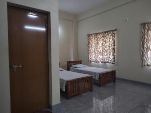 a room with two beds and a door and a window at Bridgettine Paradise in Sultan Bathery