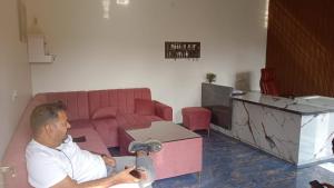 a man sitting in front of a pink couch at Riyank Farms in Patna