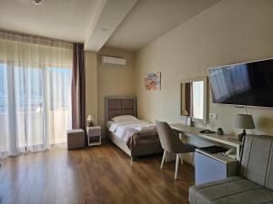 ein Schlafzimmer mit einem Bett und einem Schreibtisch mit Fernseher in der Unterkunft Hotel Olimpija plus in Herceg-Novi