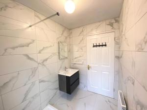 a bathroom with white marble walls and a white door at Anchors Rest, Cobh in Cobh