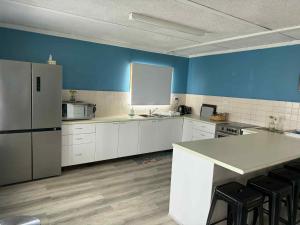 a kitchen with white cabinets and a blue wall at Cervantes Beach Shack in Cervantes