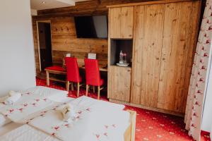 a bedroom with two beds and a table with red chairs at Panorama Hotel Leidingerhof in Mondsee