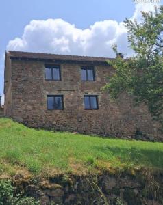 a brick building with four windows on a grass field at Les Gîtes de Sophinette in Dompierre-les-Ormes