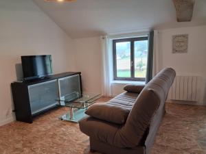 a living room with a couch and a tv at Les Gîtes de Sophinette in Dompierre-les-Ormes