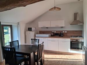 a kitchen with a table and chairs and a kitchen with white cabinets at Les Gîtes de Sophinette in Dompierre-les-Ormes