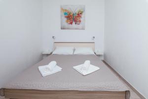 a bed with two white towels on top of it at Apartmani AE in Biograd na Moru