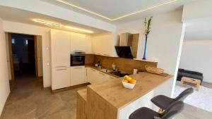 a kitchen with white cabinets and a counter with two chairs at Luxus Terrassenappartement Berg & See 2 in Bodensdorf