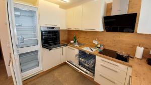 a kitchen with an open refrigerator and a sink at Luxus Terrassenappartement Berg & See 2 in Bodensdorf +34 photos