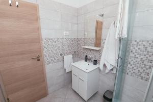 a white bathroom with a sink and a shower at Apartmani AE in Biograd na Moru +34 photos