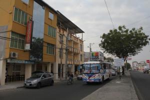 um autocarro a descer uma rua da cidade ao lado de um edifício em Hostal Rosa Mar em Manta