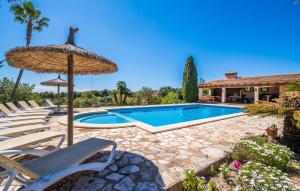 a swimming pool with chairs and an umbrella at Can Palleta Nou in S'Horta