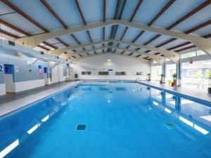 a large indoor swimming pool with blue water at Chalet 58 - The Beach House in Deal