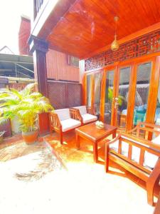 a porch with benches and tables on a house at Villa Chaluenxay Boutique Hotel 2 in Luang Prabang