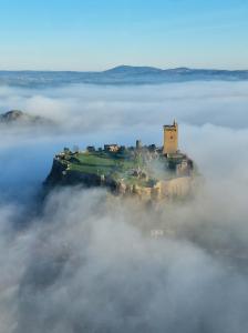 an island in the fog with a castle on it at La Velaysienne 5 étoiles piscine,sauna, jacuzzi in Le Monteil