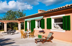 a patio with chairs and a table with green shutters at Santa Maria in Artá