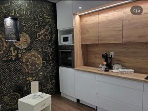 a kitchen with white cabinets and a black and brown wall at Apartman Delux in Bačka Topola +88 photos