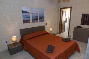 a bedroom with a bed with orange sheets and two lamps at Ta Marija in Żebbuġ