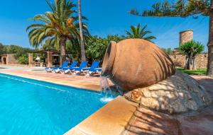 a water fountain next to a swimming pool with chairs at Bosco in Sa Coma