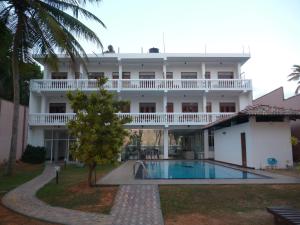 a large white building with a swimming pool in front of it at Hotel Ocean View Cottage in Hikkaduwa