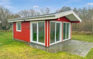 a red shed with glass doors in a field at Beach Front Home In Samsø With House Sea View in Kolby Kås