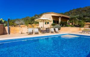 a swimming pool with chairs and an umbrella next to a house at Can Safiro in Son Servera +44 photos