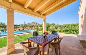 a wooden table and chairs on a patio with a pool at S'hortet Gran in Alcudia