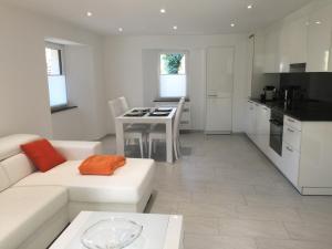 a living room with a white couch and a kitchen at Casa in Selva in Cavergno