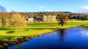 a river with a large building in the background at 1885 The Retreat in Matlock