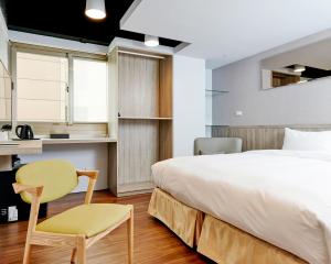 a bedroom with a bed and a chair and a table at Bon Hotel Taipei in Taipei