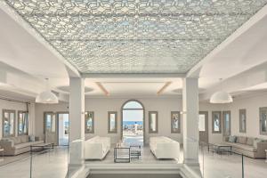 a lobby with white chairs and tables and a ceiling at Aqua Blue Beach Hotel in Perissa