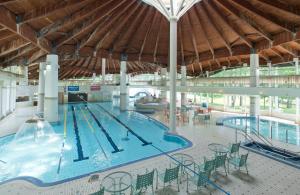a swimming pool in a large building with a large ceiling at Kusatsu Onsen Hotel Village in Kusatsu