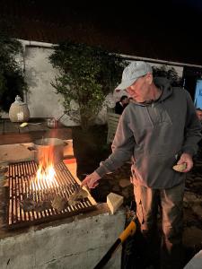a man is cooking food on a grill at Camønogaarden B&B, darksky cabins and events in Borre +55 photos