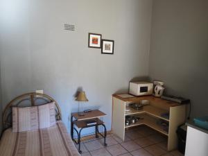 a bedroom with a bed and a desk with a microwave at De Villas Guesthouse in Ermelo